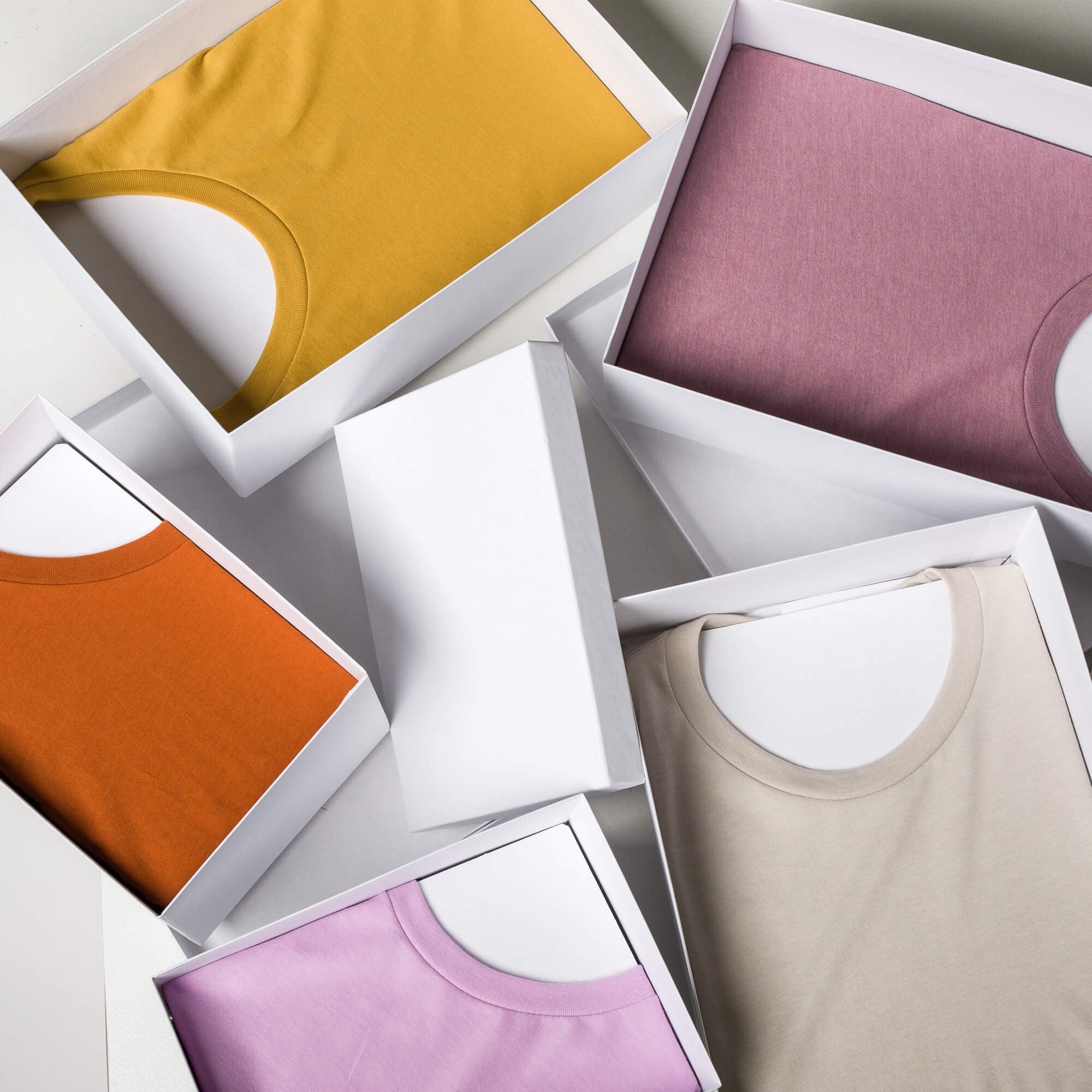 Assorted printful t shirts folded in white packaging boxes